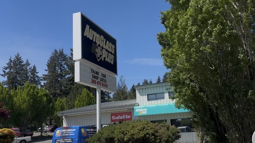 Auto Glass Plus sign with a Safelite sign on the building behind it